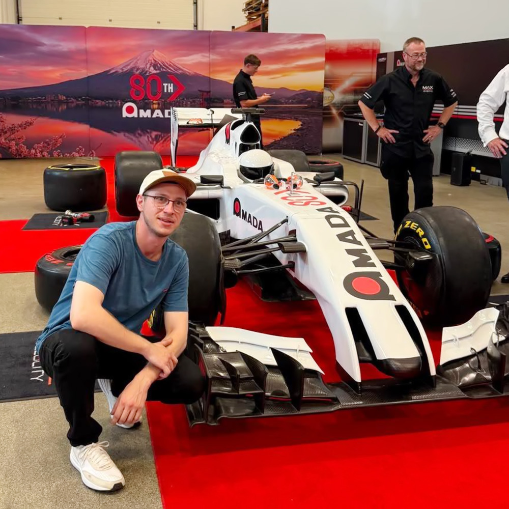 Universal Fabrications employee in front of racing car at Amada 80th celebrations