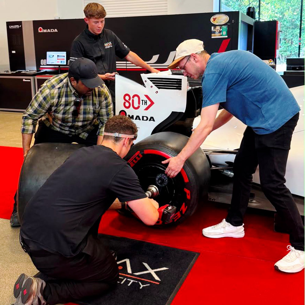 Universal Fabrications employees changing racing car wheel at Amada 80th celebrations