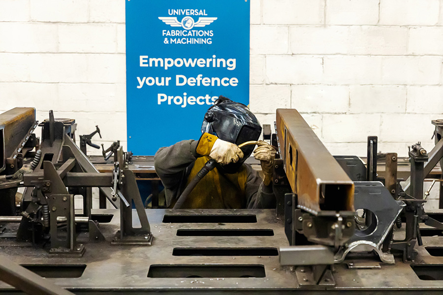 Welder welding a large steel fabrication in a precision welding fixture at Universal Fabrications in Coventry